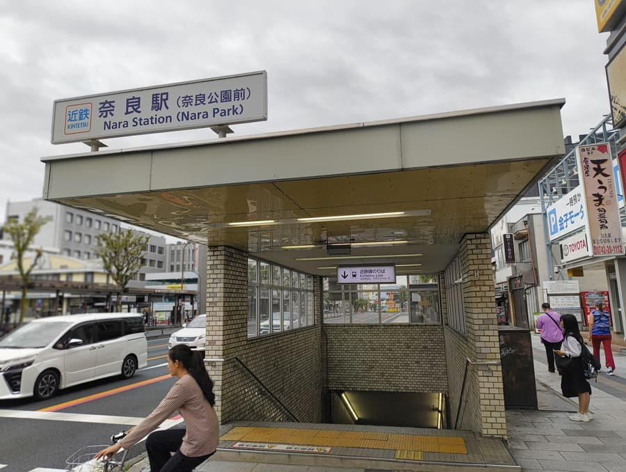 The street entrance to Kintetsu-Nara station, its blue sign reading Nara Station (Nara Park), with steps leading down to the platforms.