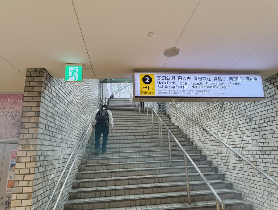 The stairs up to Exit 2 at Kintetsu-Nara, under a sign listing Nara Park, Todaiji Temple, Kasugataisha Shrine, Kohfukuji Temple and the Nara National Museum.