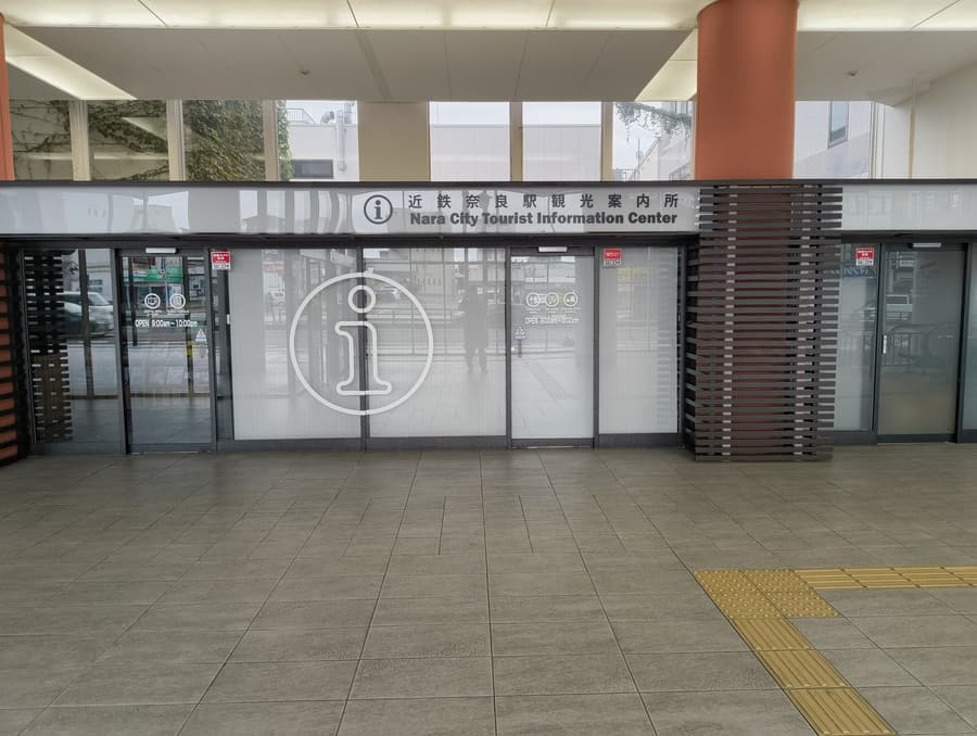 The glass frontage of the Nara City Tourist Information Center beside Kintetsu-Nara station, its door marked open 9:00am to 10:00pm.