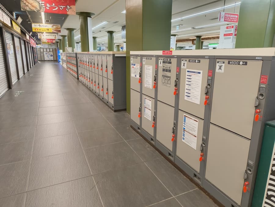 A long row of coin lockers along an underground corridor at Kintetsu-Nara station, each door marked with its price.